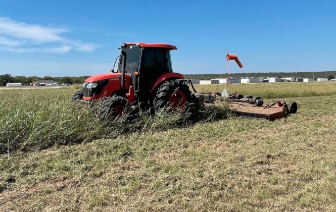 Red tractor clearing overgrown acreage on a rural lot