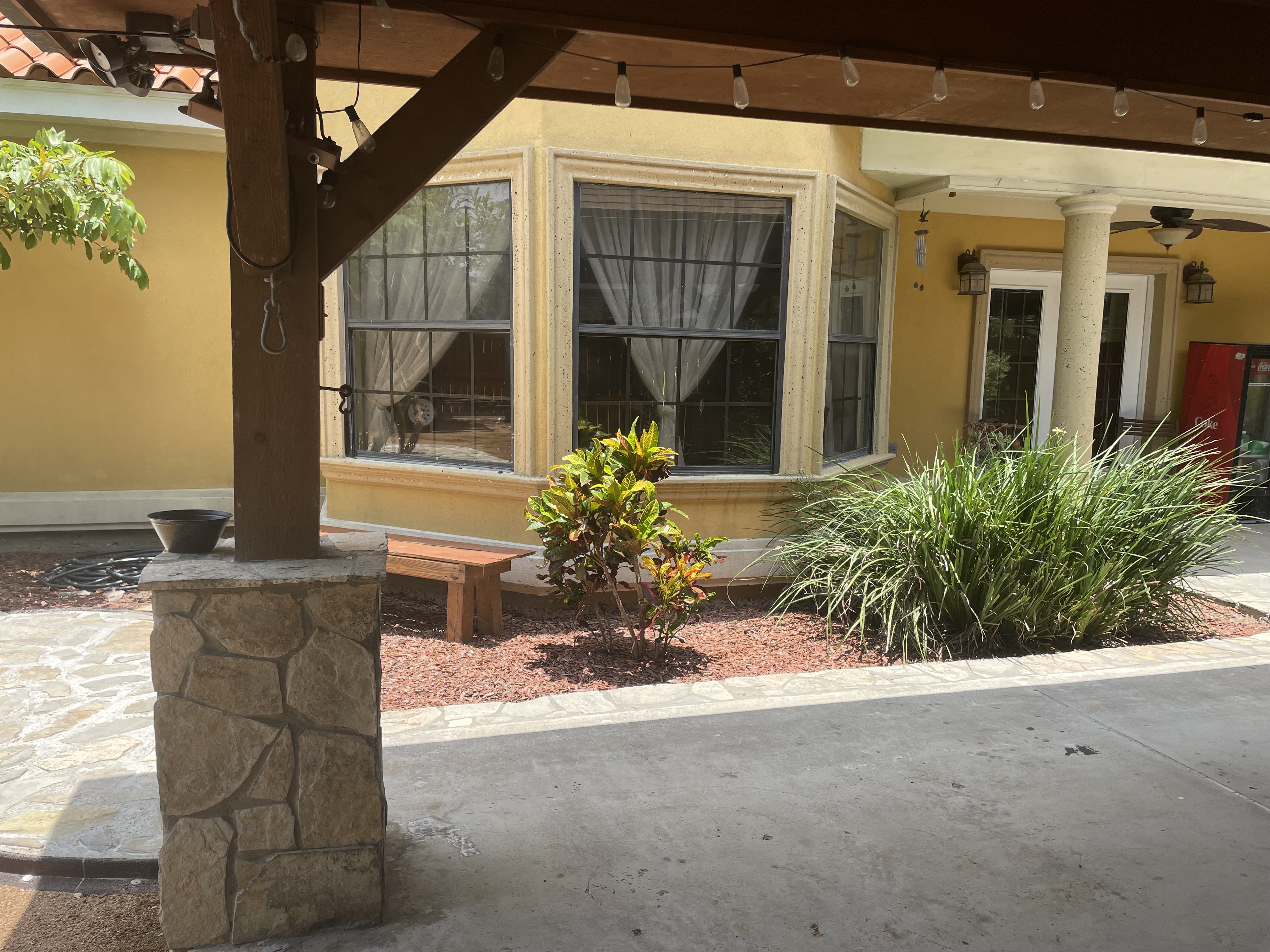 Covered patio with stone columns, pergola, and landscaping