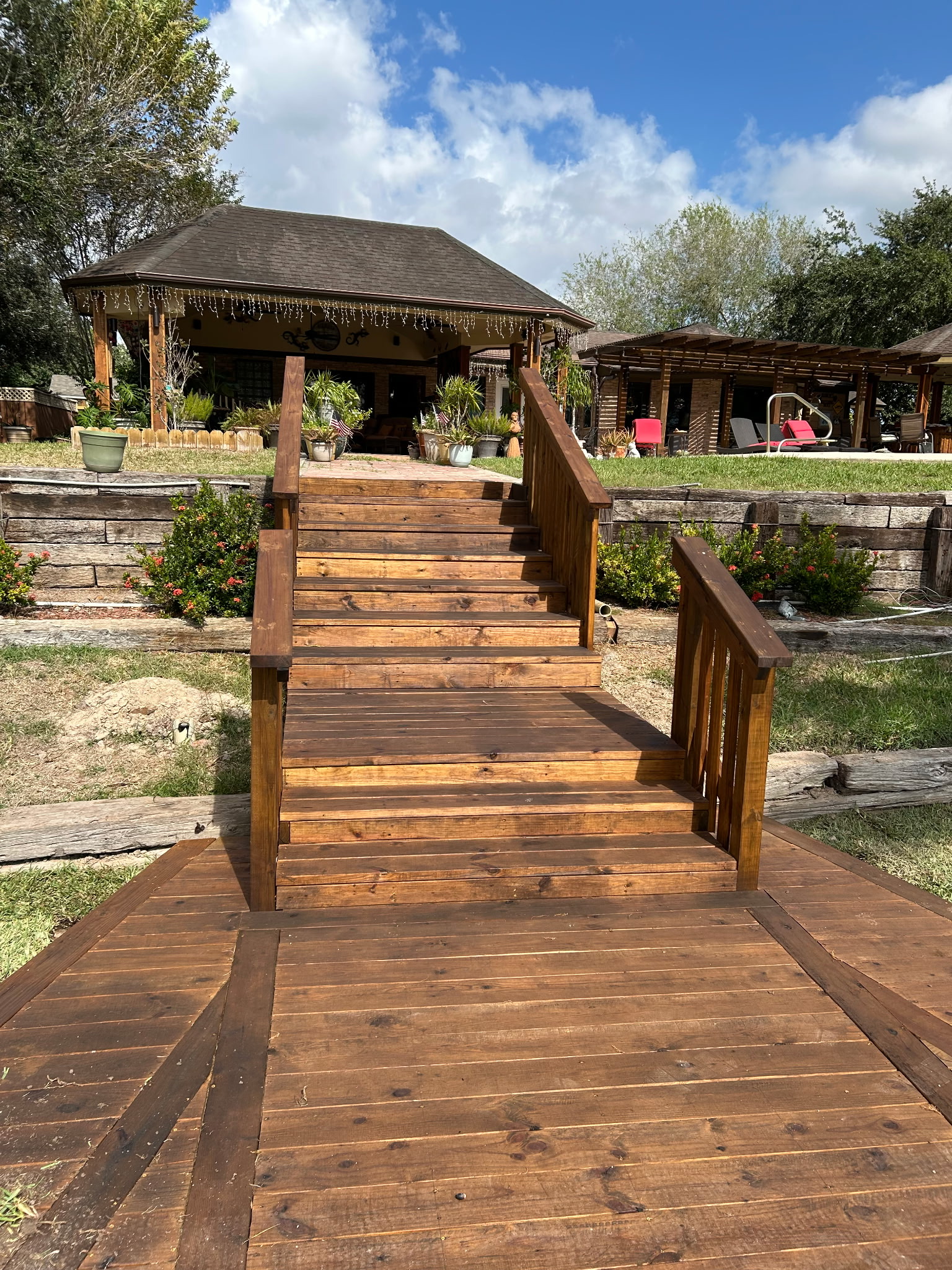 Stained wood dock with stairs leading up to a covered pavilion — Texas Land Creations